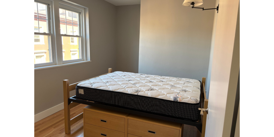 a bedroom with a bed, dresser and window