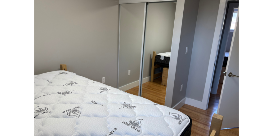 a bedroom with a bed, mirror and closet