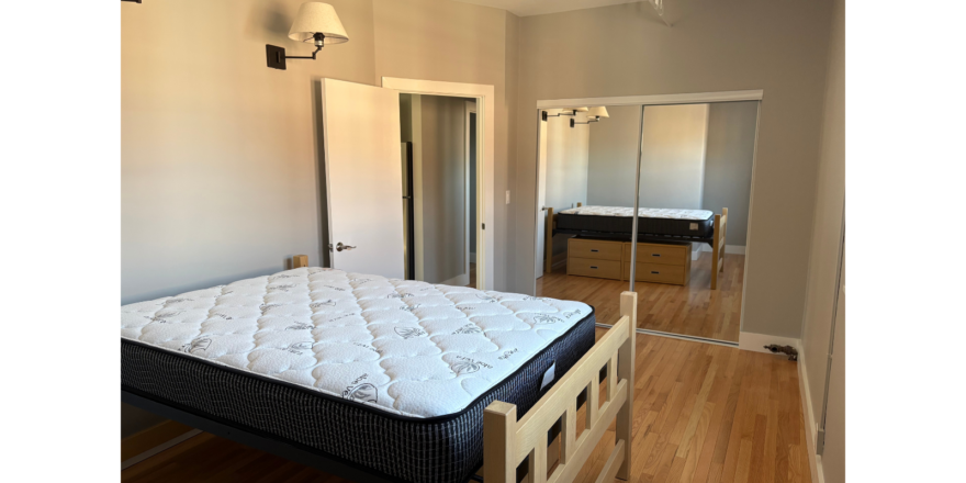 a bedroom with a bed, dresser and mirror