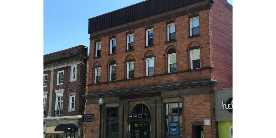 a row of cars parked in front of a tall brick building