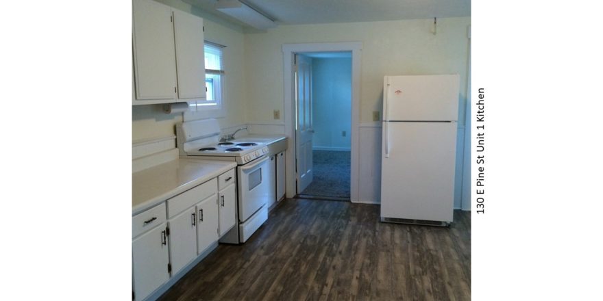 Kitchen with wood-style floor, white appliances, white cabinets, and light-colored countertops