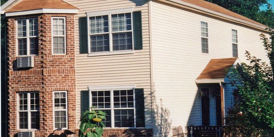 Exterior of townhome with brick and siding as well as covered entrances and large windows