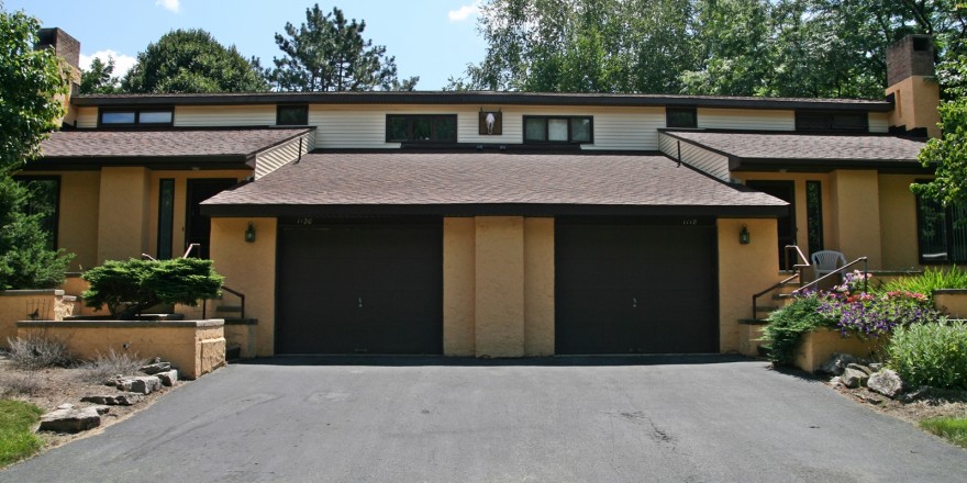 Exterior of duplex with large garage and yellow stucco siding