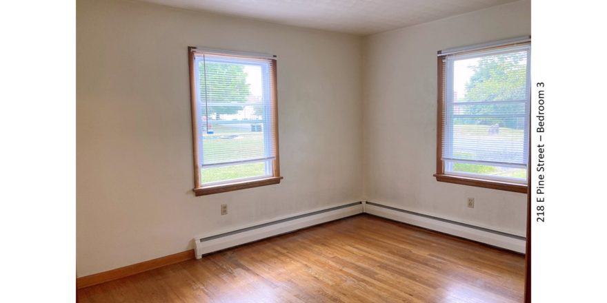Unfurnished bedroom with hardwood floors and windows