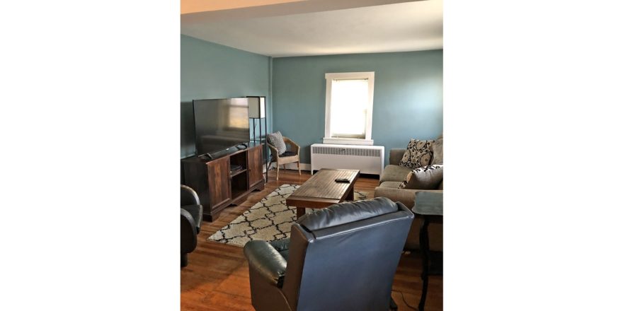 Living room with coffee table, two leatherette recliners, suede couch, TV and entertainment center