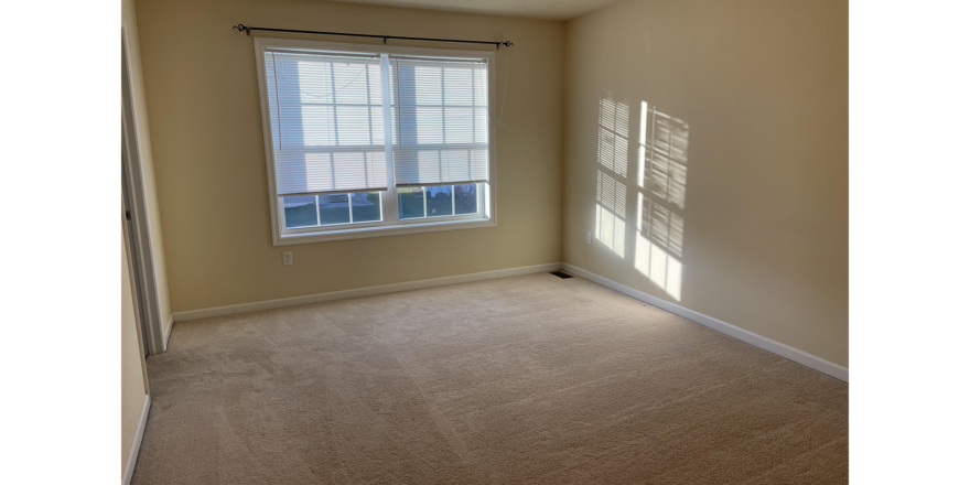 an empty room with two windows and a carpeted floor