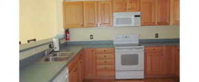 Kitchen with wood-tone cabinets, double bowl sink and white appliances