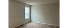 an empty room with a window and a ceiling fan