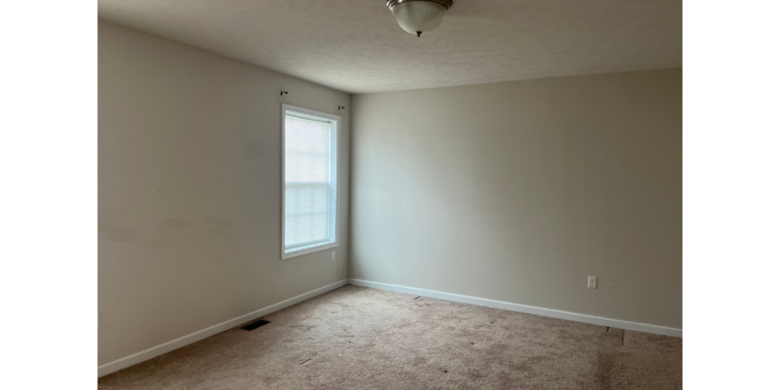 an empty room with a window and a ceiling fan