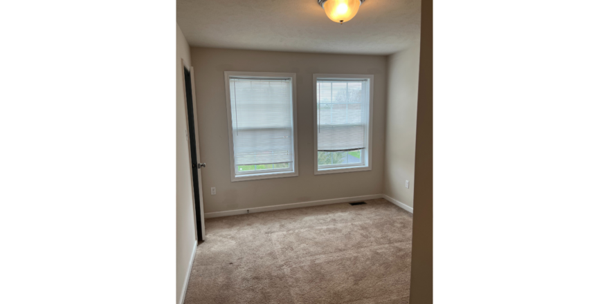 an empty room with two windows in it