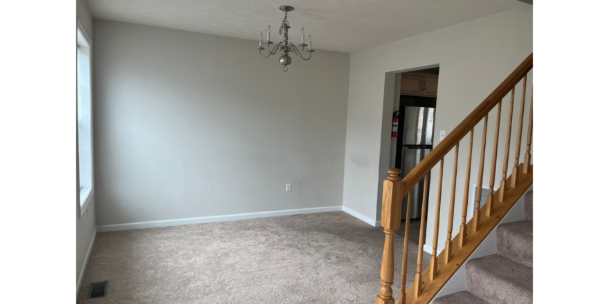 an empty room with stairs and a chandelier