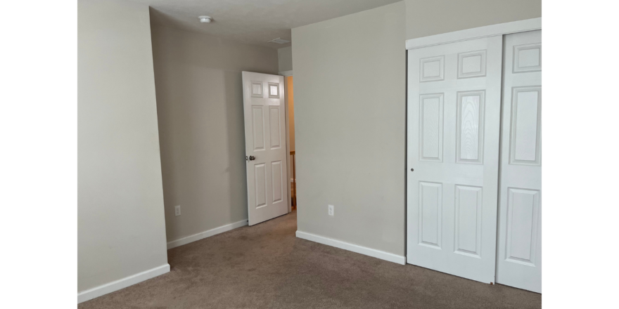 an empty room with a door and a closet