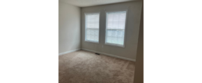an empty room with two windows and carpet