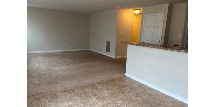 an empty living room with a bar in the corner
