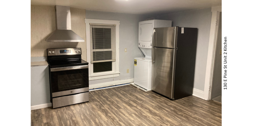 Kitchen with window, washer dryer, stainless steel stove and fridge. LVP flooring.