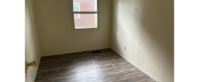 an empty room with wood floors and a window
