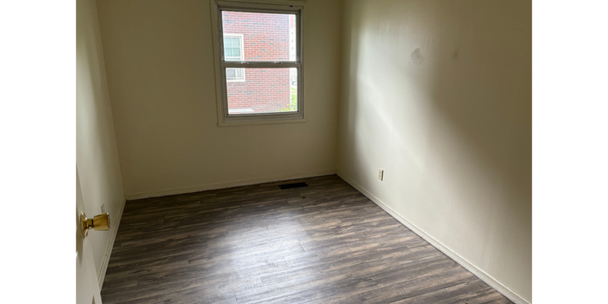 an empty room with wood floors and a window