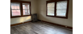 an empty room with wood floors and windows