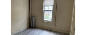an empty room with a radiator and a window