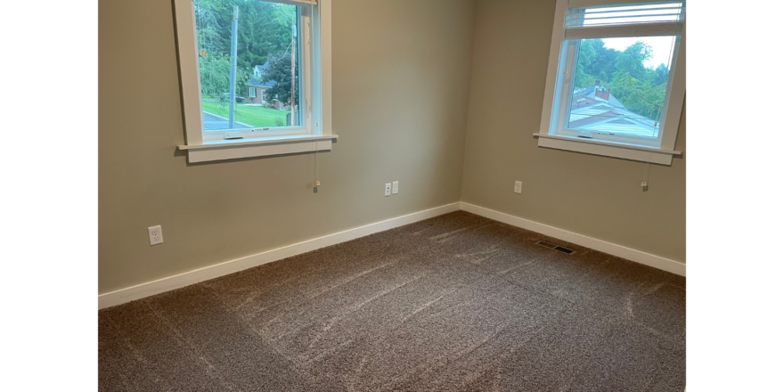 a empty room with two windows and a carpeted floor