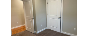 an empty room with two white doors and a hard wood floor