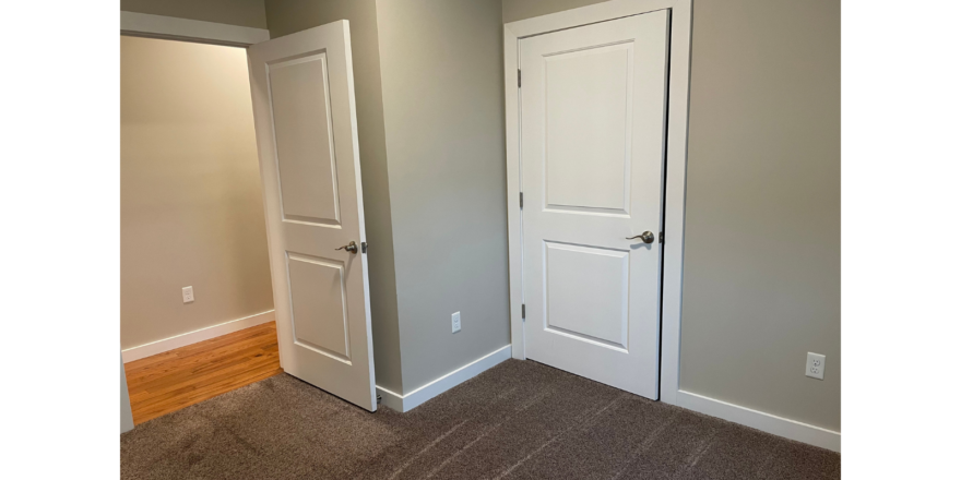 an empty room with two white doors and a hard wood floor