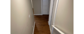 a narrow hallway leading to a door and a closet