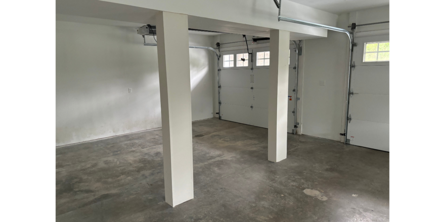 an empty garage with two garage doors open