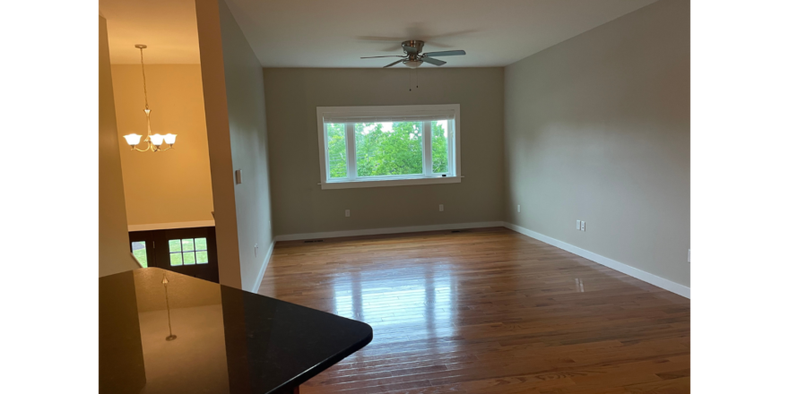 an empty living room with a ceiling fan