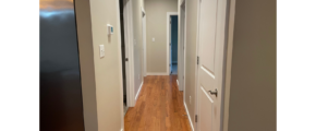 a long narrow hallway with wood floors and white walls