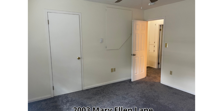 an empty room with a ceiling fan and a door