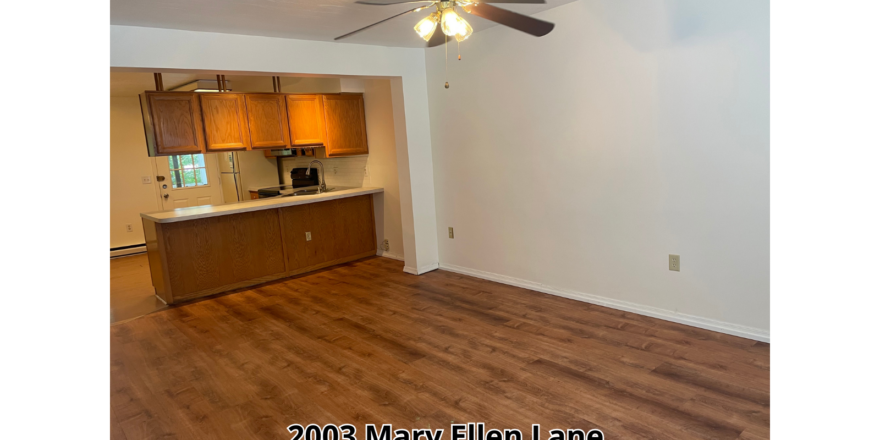 an empty living room with a ceiling fan