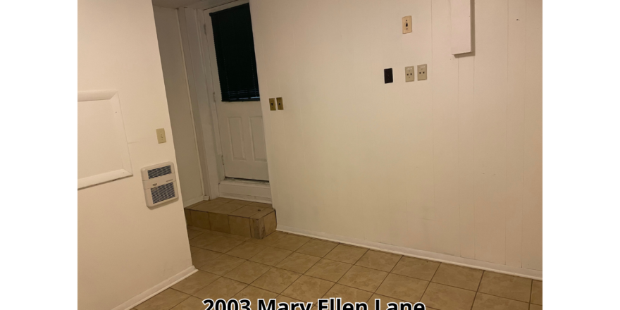 an empty room with a white door and tile floor