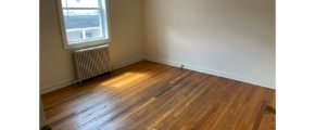 an empty room with wood floors and a radiator