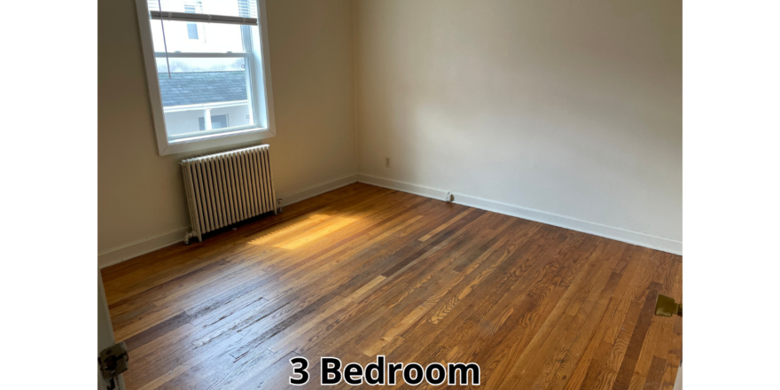 an empty room with wood floors and a radiator