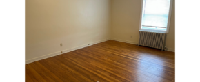 an empty room with wood floors and a radiator