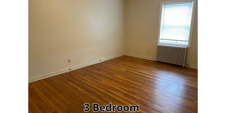 an empty room with wood floors and a radiator
