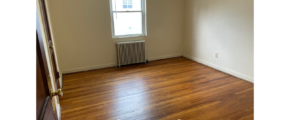 an empty room with wood floors and a radiator