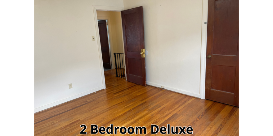 an empty room with two doors and a hard wood floor