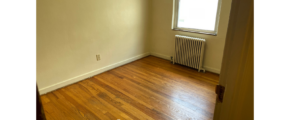 an empty room with wood floors and a radiator