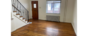 an empty room with a wooden floor and stairs