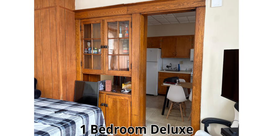a bedroom with a bed, desk, and cupboards