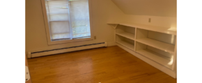 an empty room with a book shelf and a window