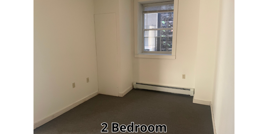 an empty room with a window and a radiator