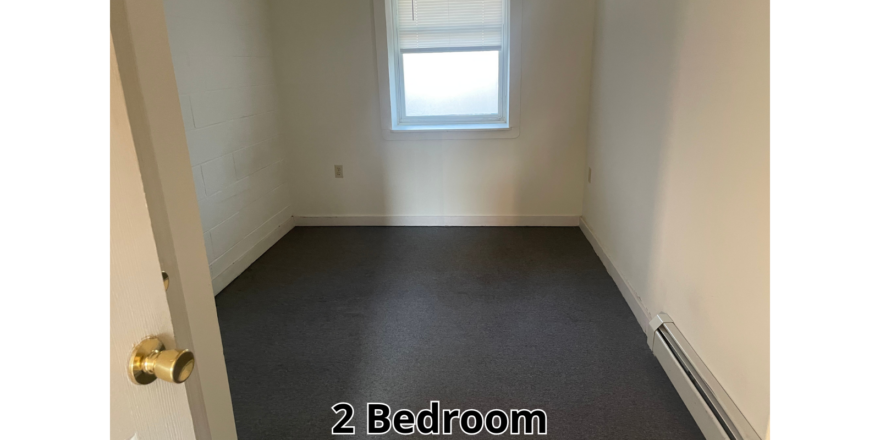 an empty room with a window and a radiator