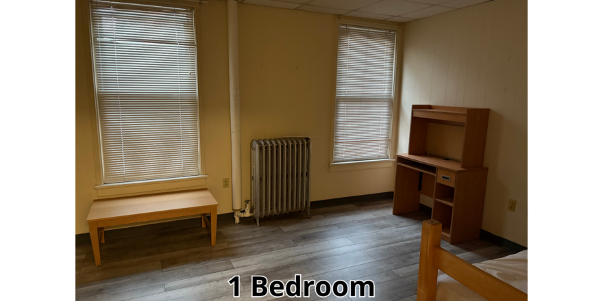 a bedroom with a bed, desk, and a radiator