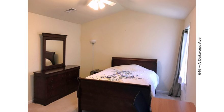 Bedroom with queen bed, dresser with mirror, and lamp