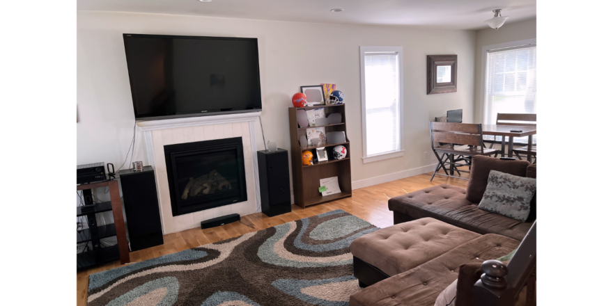 Living room with electric fireplace, large TV, sectional sofa, and dining table