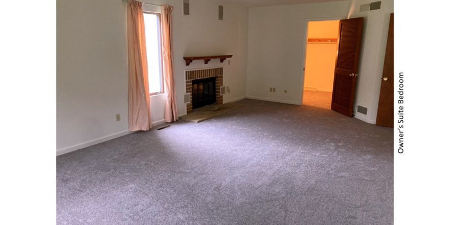Owner's suite bedroom with gas fireplace and large windows