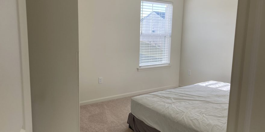 an empty bedroom with a bed and window